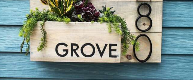 Plant box with a last name and address number hanging near front door of a home