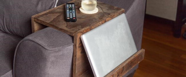 Couch organizer with remote, glass of water, and laptop