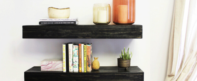 Two floating shelves holding books, plants, and candles