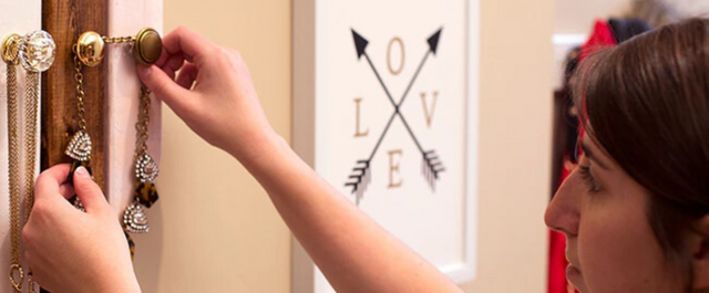 Woman hanging jewelry on an on-wall organizer
