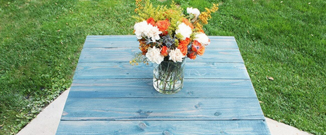 Wooden table outside with flowers and grass