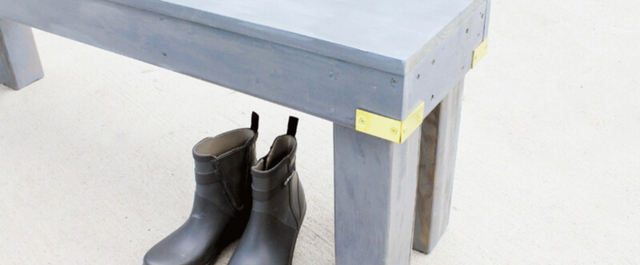 Grey bench outside with a pair of rain boots sitting underneath