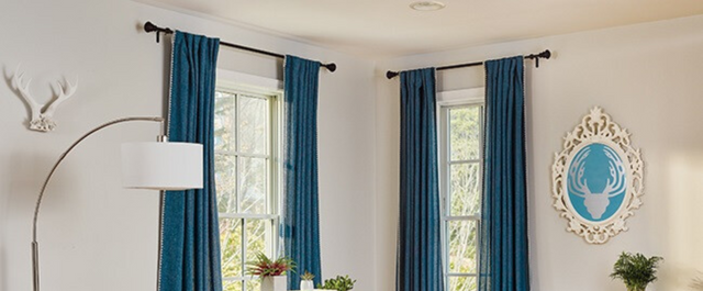 Two windows in the corner of a room with blue curtains