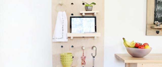 Pegboard with hand towels and plants on wall next to kitchen counter and chalkboard