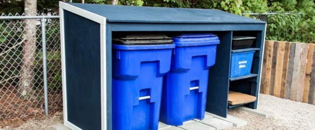 Recycling bins under cover of a wooden recycling shed