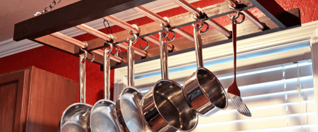 Pots and pans hanging from an overhead kitchen rack