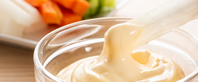 close up shot of mayo with vegetables in the background