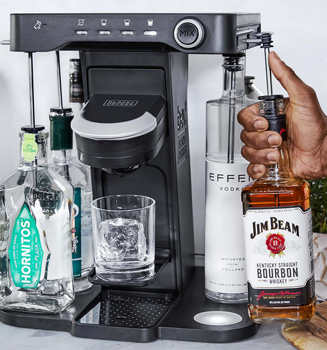 close-up, on the patio, of a man's hand loading a bottle of whiskey into the easy load liquor system on the bev by BLACK+DECKER™ cocktail maker