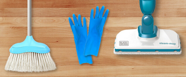Broom, rubber gloves, and steam mop on wood floor