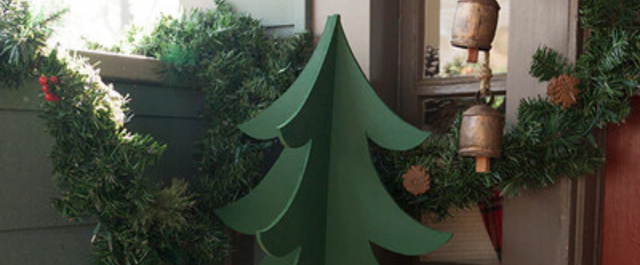 Miniature wooden Christmas tree in corner of room with other Christmas garland and decorations