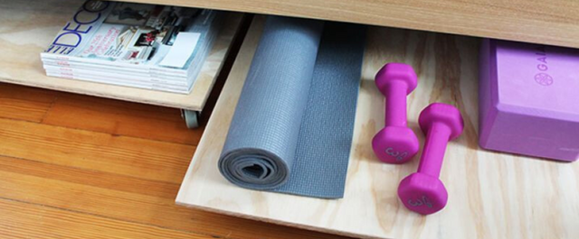 Yoga mat and other workout equipment on rolling shelf under a table