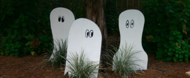 Three wooden ghost decorations in front yard