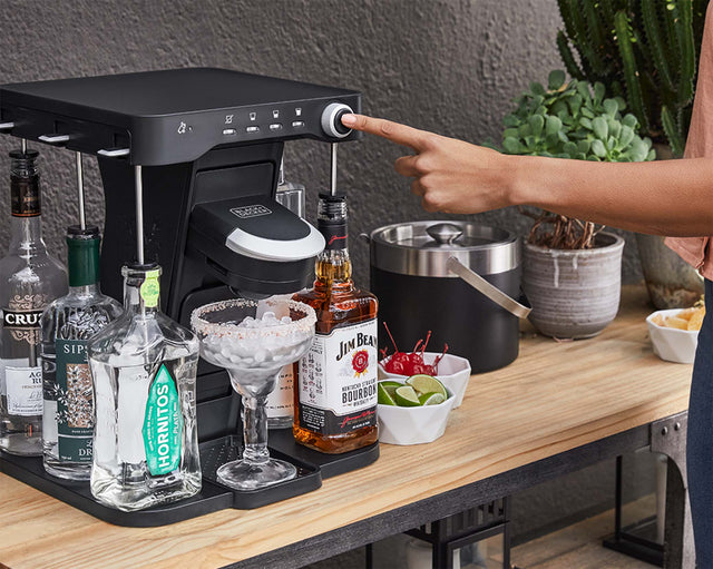 woman, on the patio, pressing the mix button on the bev by BLACK+DECKER™ cocktail maker to make a margarita